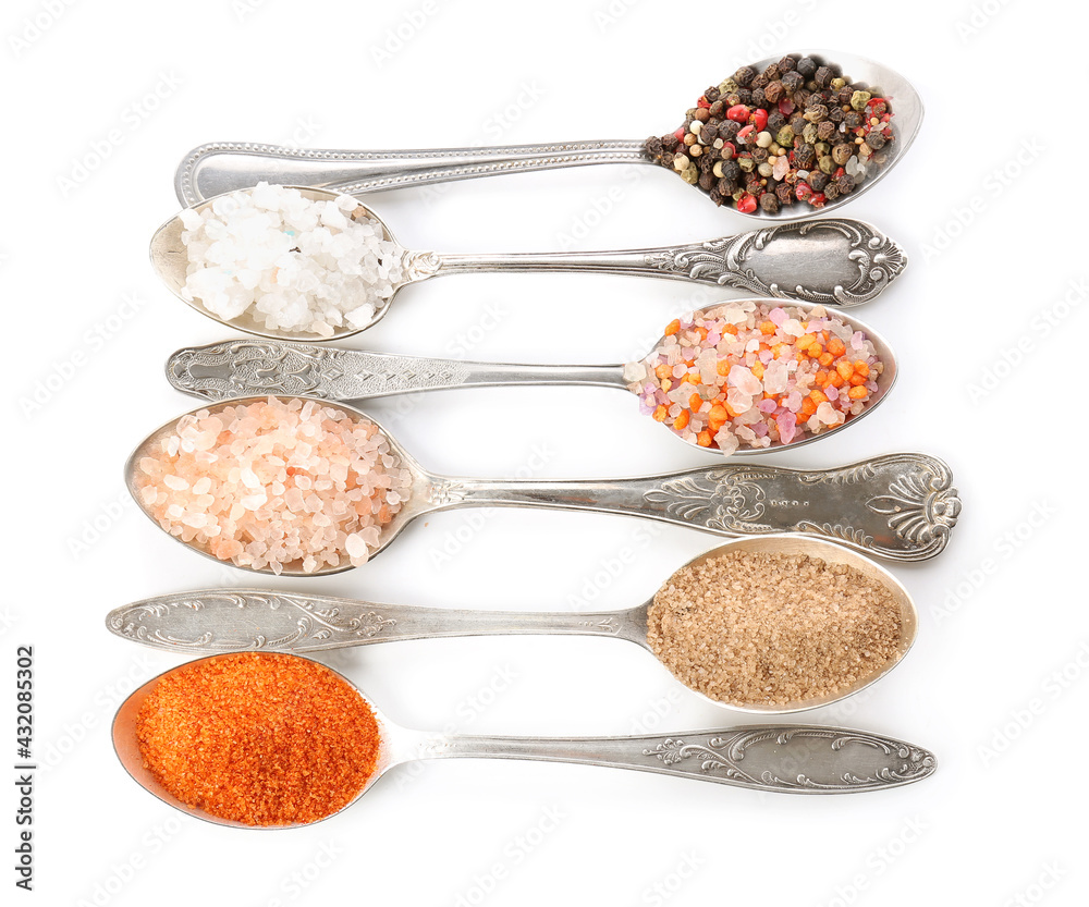 Spoons with different salt and spices on white background