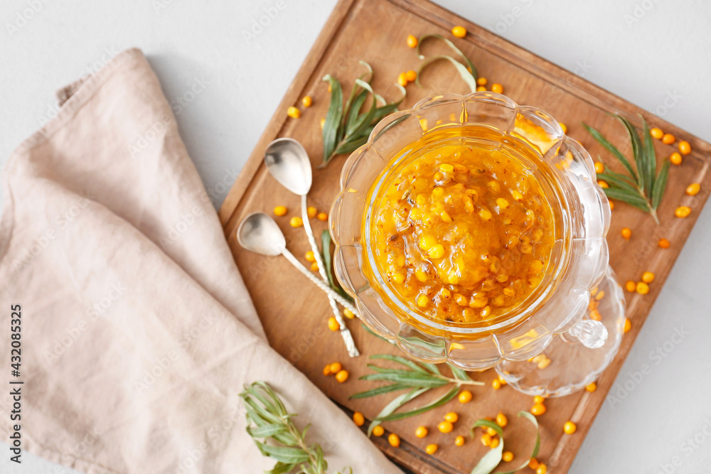 Bowl of healthy sea buckthorn jam on light background