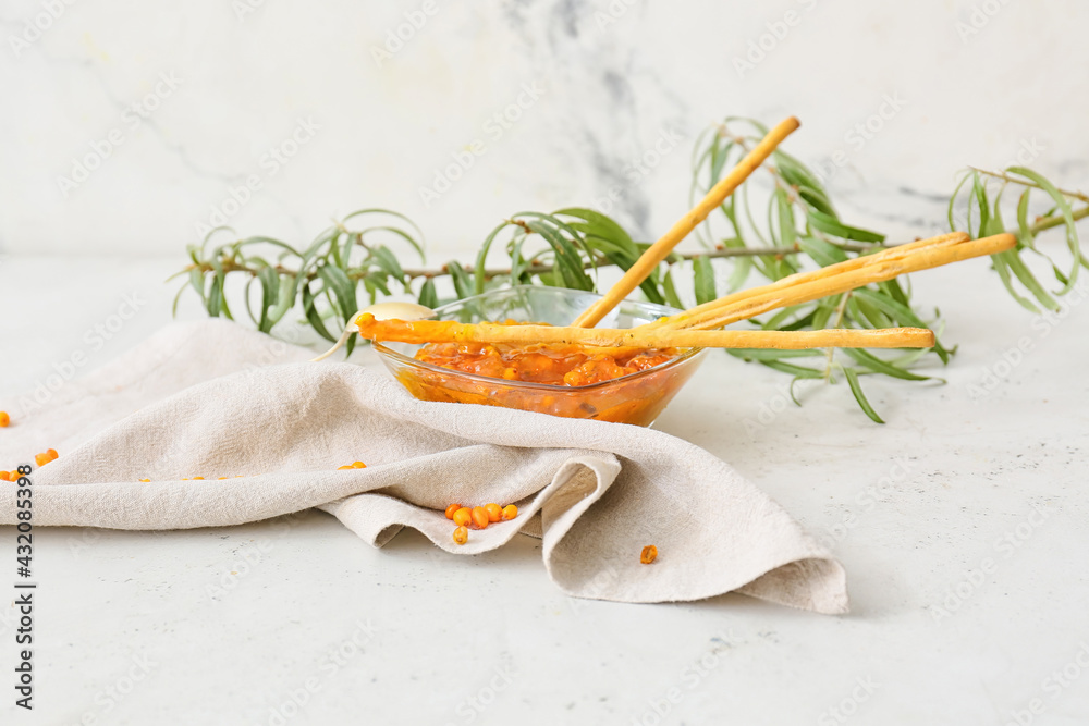 Bowl of healthy sea buckthorn jam and bread sticks on white background