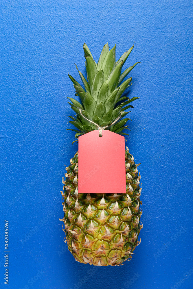 Fresh pineapple with shopping tag on color background