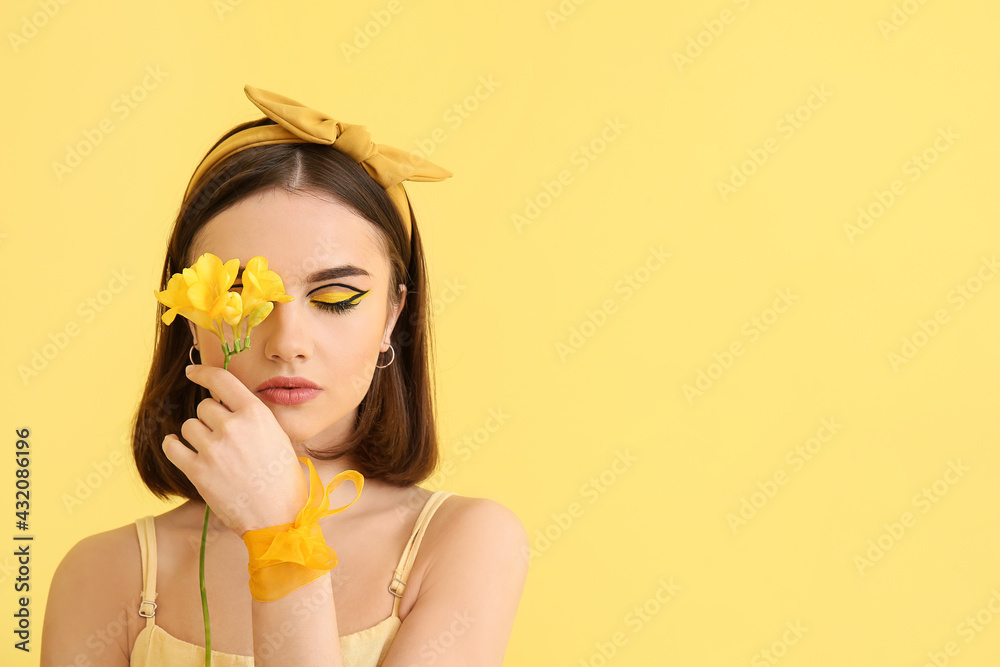 Stylish young woman with flower on yellow background