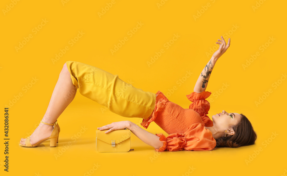 Lying young woman with bag on yellow background