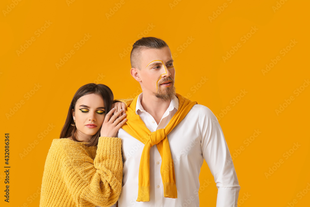 Stylish young couple on yellow background