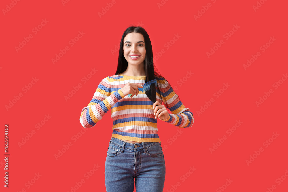 Beautiful young woman with hair comb on color background