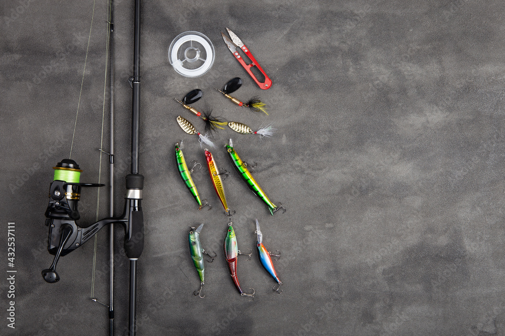 Fishing tackle - fishing spinning rod, hooks and lures on gray background. Active hobby recreation c