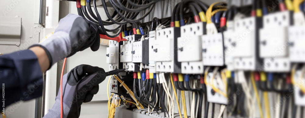 Electrician engineer tests electrical installations and wires on relay protection system. Adjustment