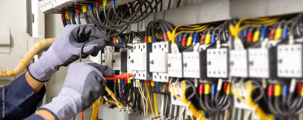 Electrician engineer tests electrical installations and wires on relay protection system. Adjustment