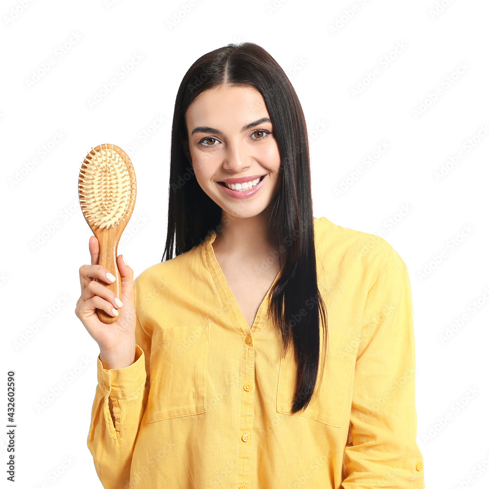 Beautiful young woman with hair brush on white background