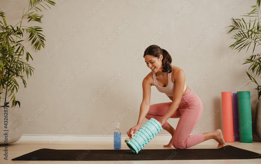 Woman disinfecting exercise roller in fitness studio