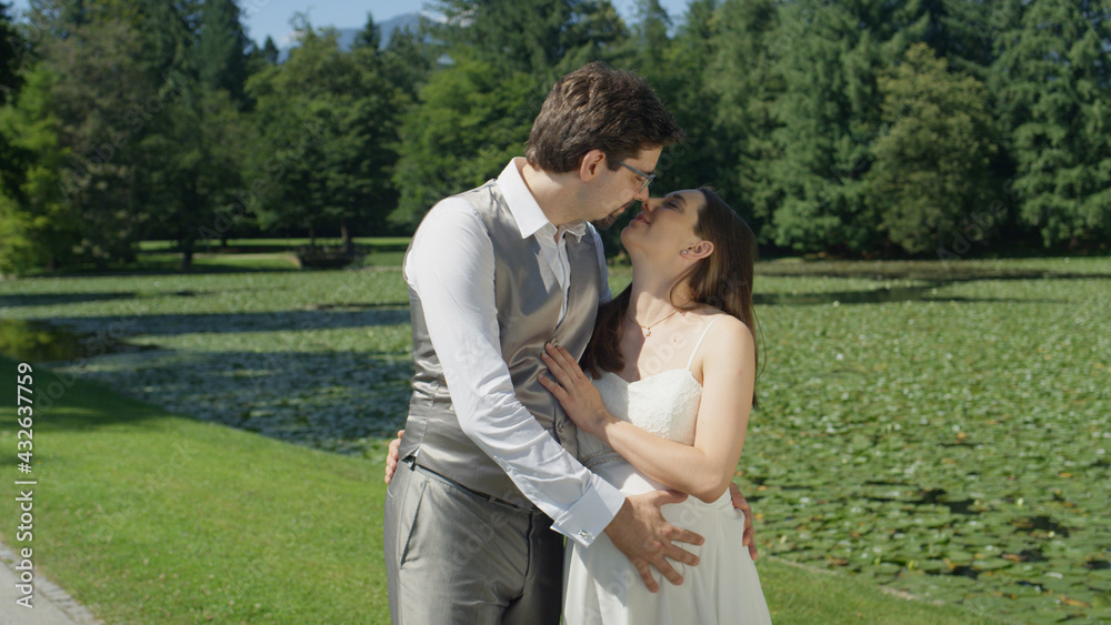 Embraced young couple in love share an intimate kiss in a beautiful sunlit park