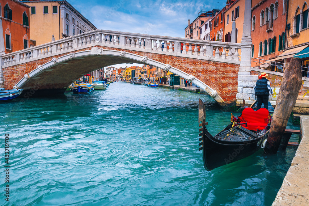 Moored boats and bridge over water canal in Venice, Italy