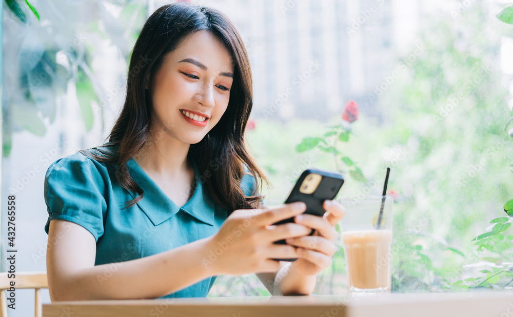 Young Asian woman using smartphone to working at cafe