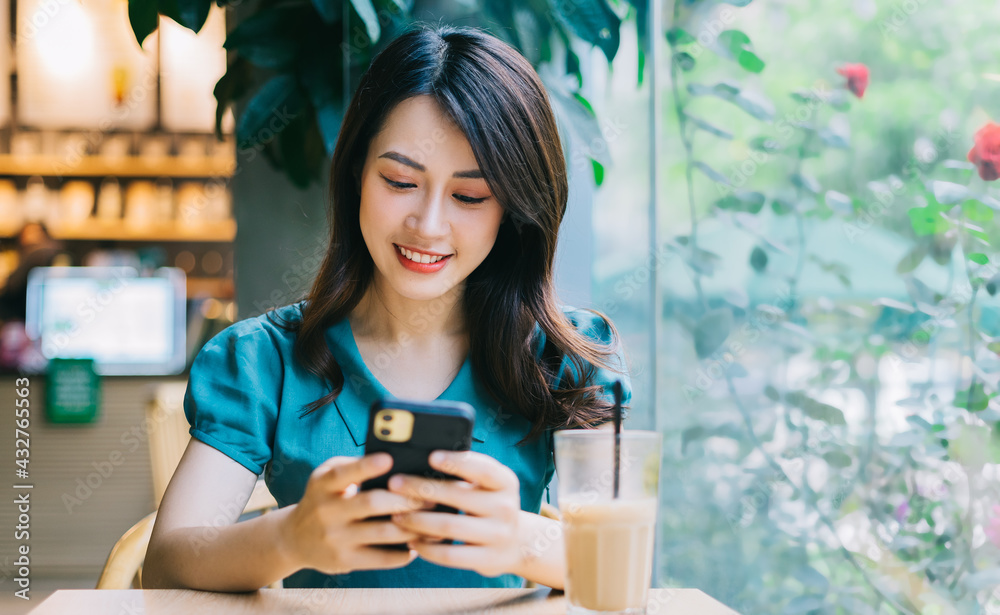 Young Asian woman smiling while using smartphone