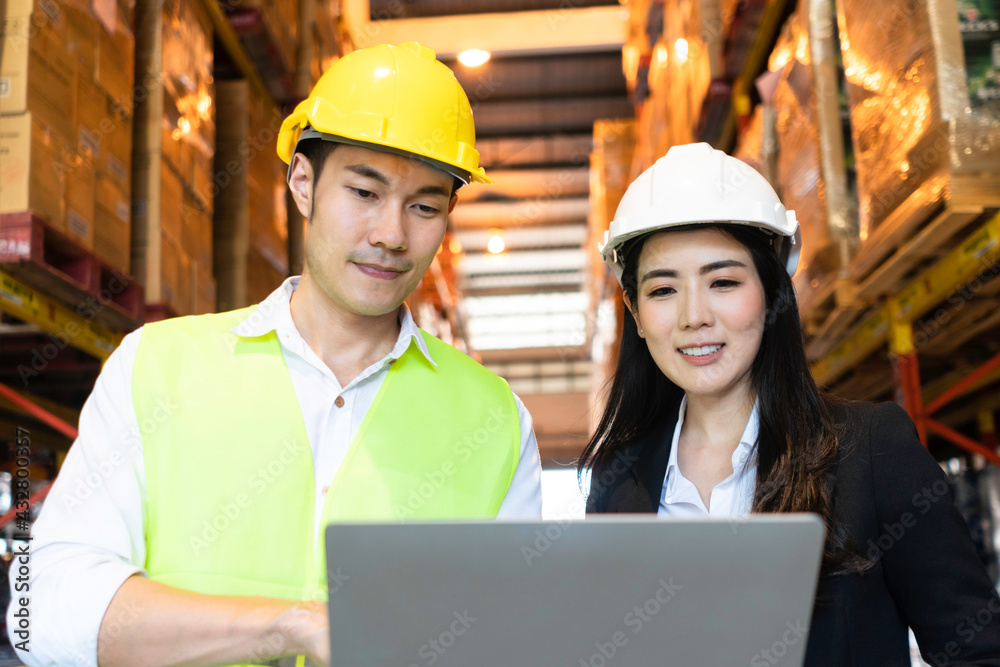 Asian male factory worker presenting work project to female company manager, looking at stock storag