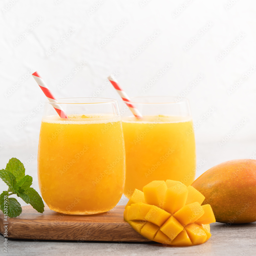 Fresh beautiful delicious mango juice smoothie in a glass cup on gray table background.