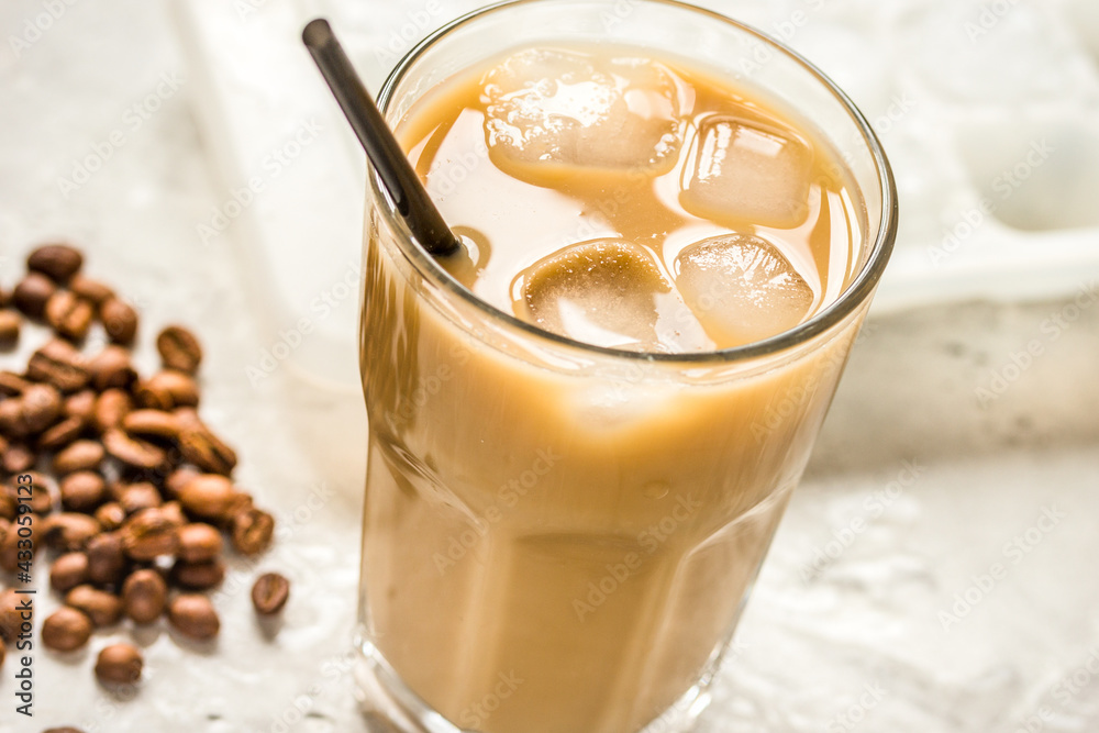 cold coffee glass with ice cubes on stone table background