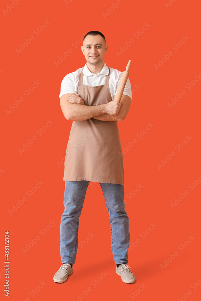 Young man with rolling pin on color background