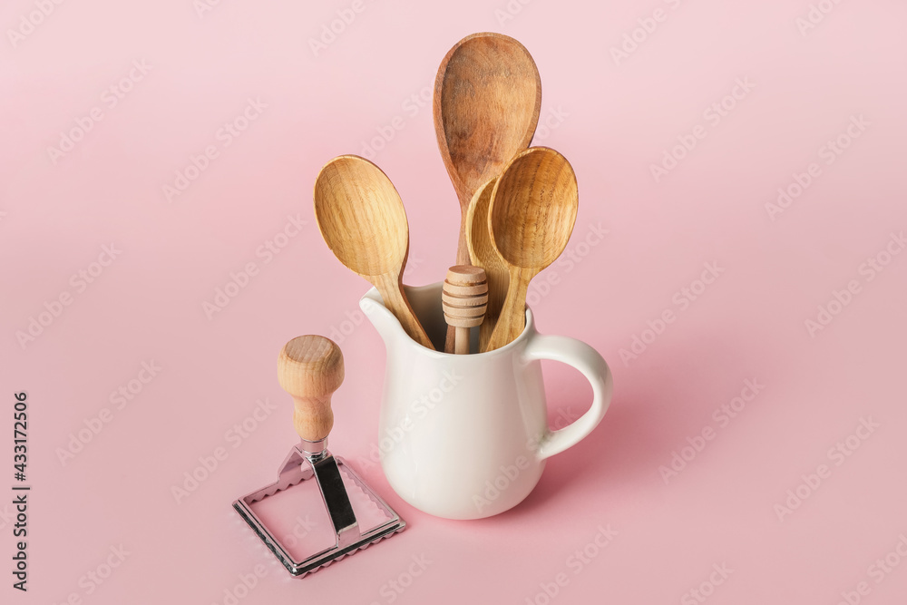 Wooden spoons and ravioli cutter on color background