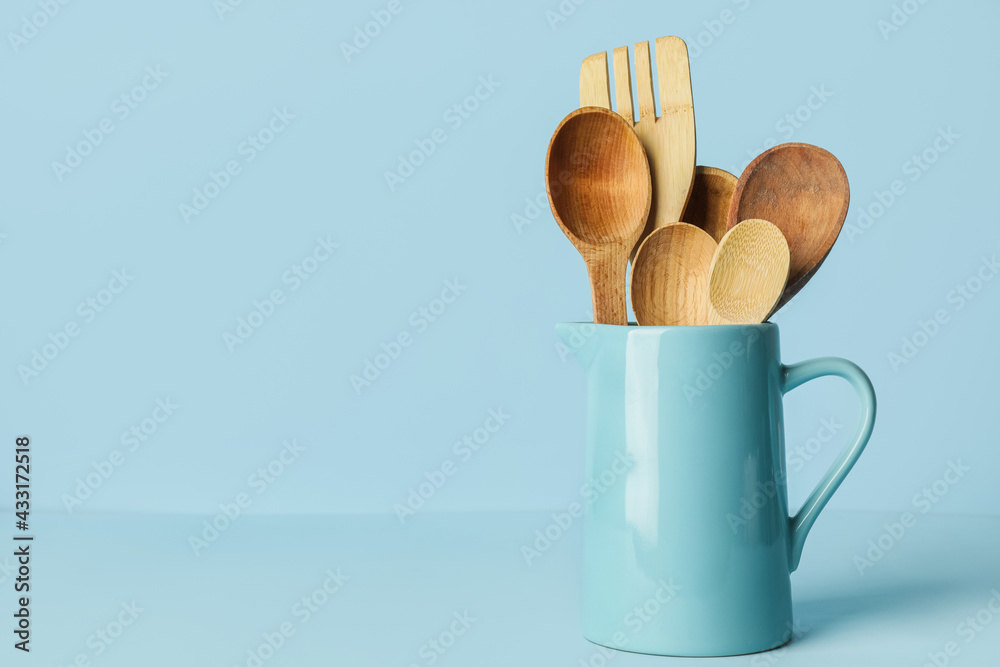 Wooden spoons and fork on color background