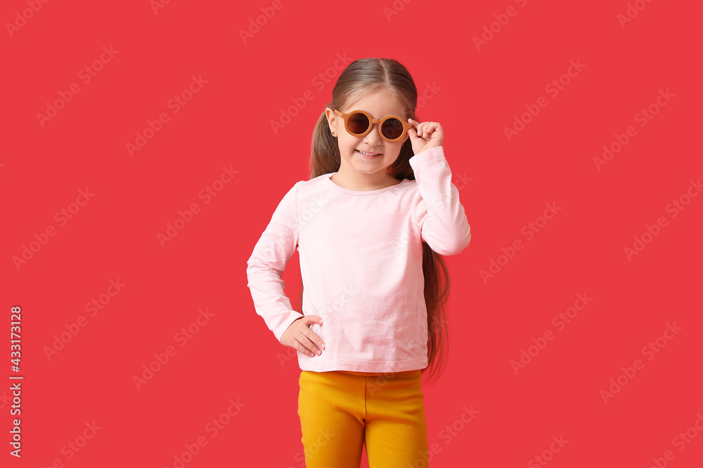 Cute little girl wearing stylish sunglasses on color background