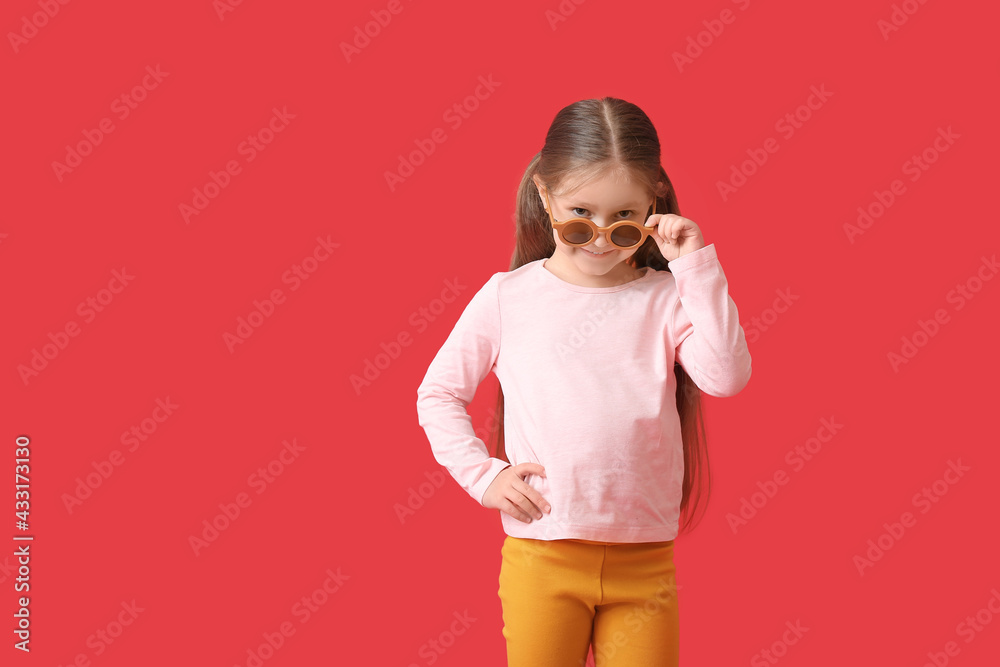 Cute little girl wearing stylish sunglasses on color background