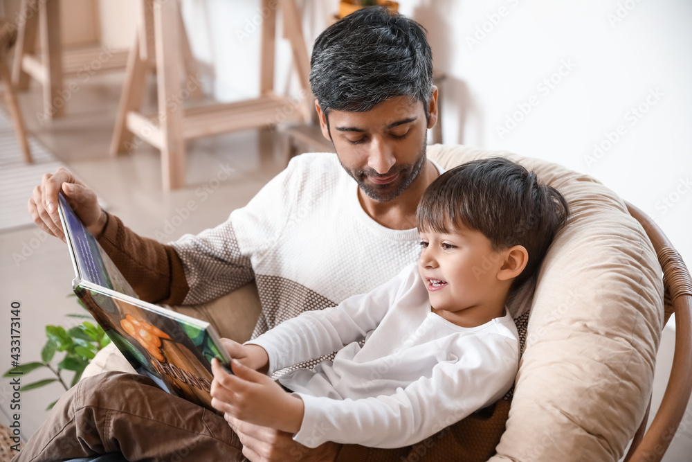 Father and little son reading book at home