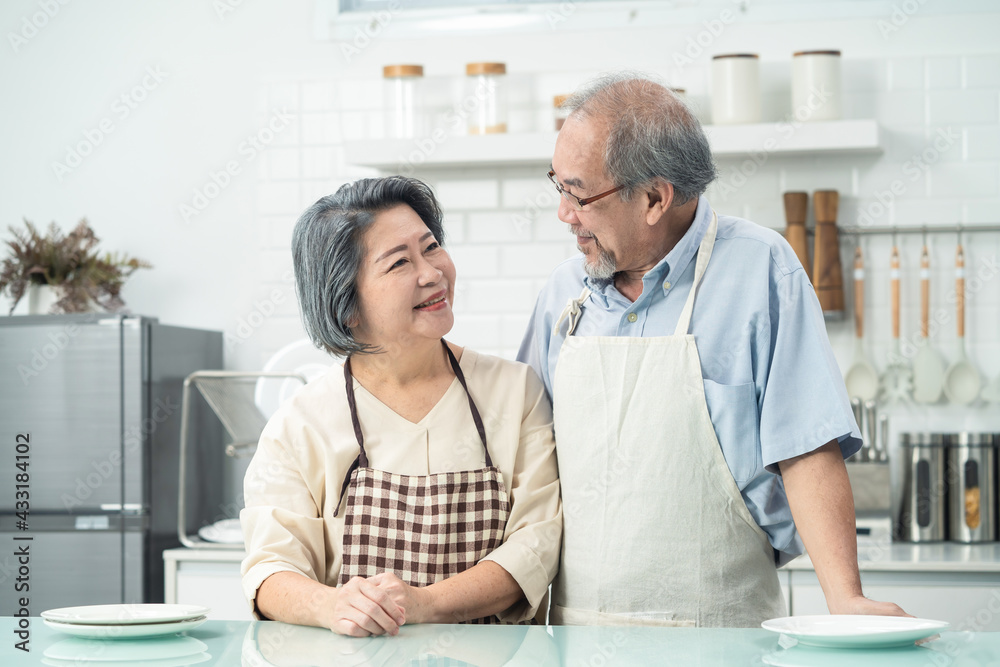 Asian grandparents couple smiling looking at each other in the kitchen