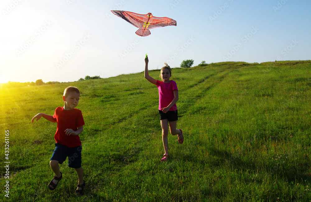 Happy kids boy and girl run with kite