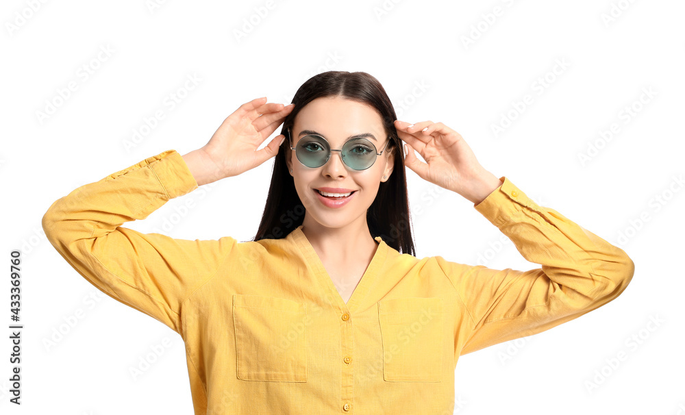 Beautiful young woman wearing stylish sunglasses on white background