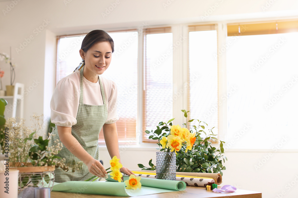 Female florist with beautiful narcissus flowers in workshop