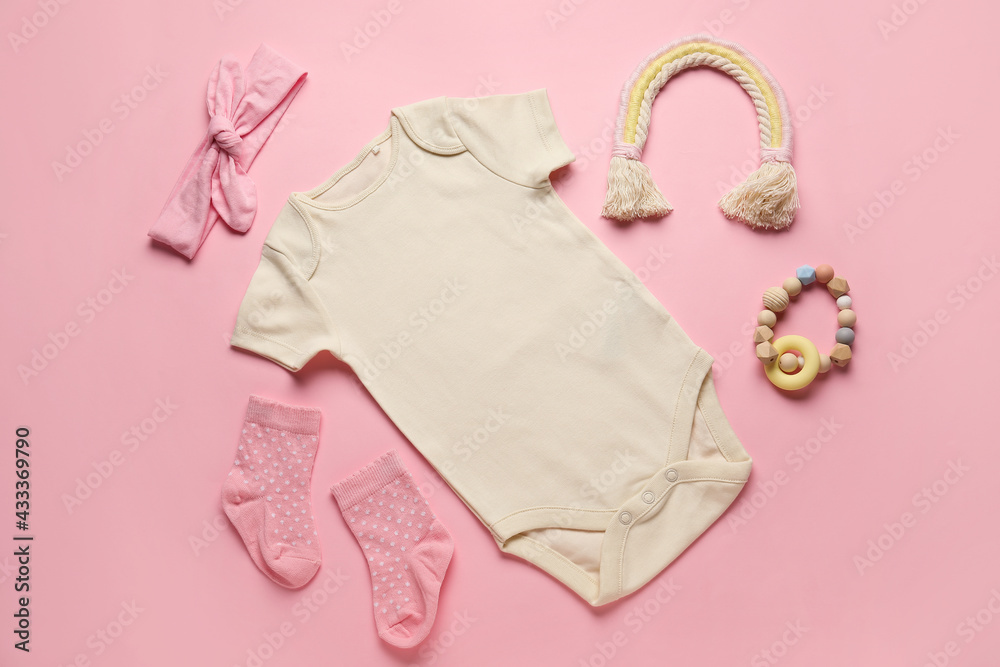 Set of baby clothes, socks and toy on color background