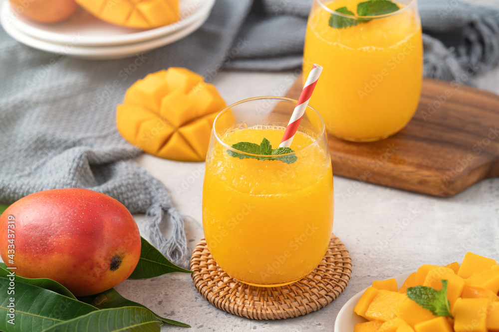 Fresh beautiful delicious mango juice smoothie in a glass cup on gray table background.