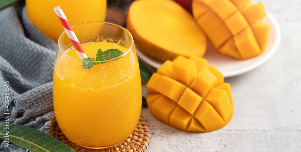 Fresh beautiful delicious mango juice smoothie in a glass cup on gray table background.