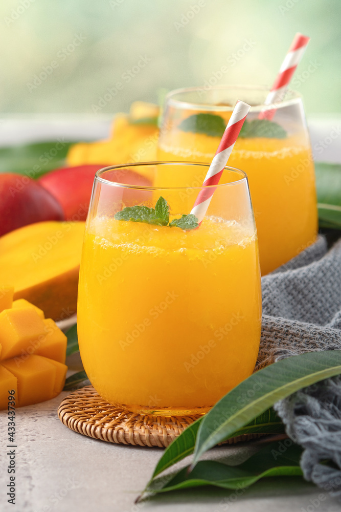 Fresh beautiful delicious mango juice smoothie in a glass cup on gray table background.