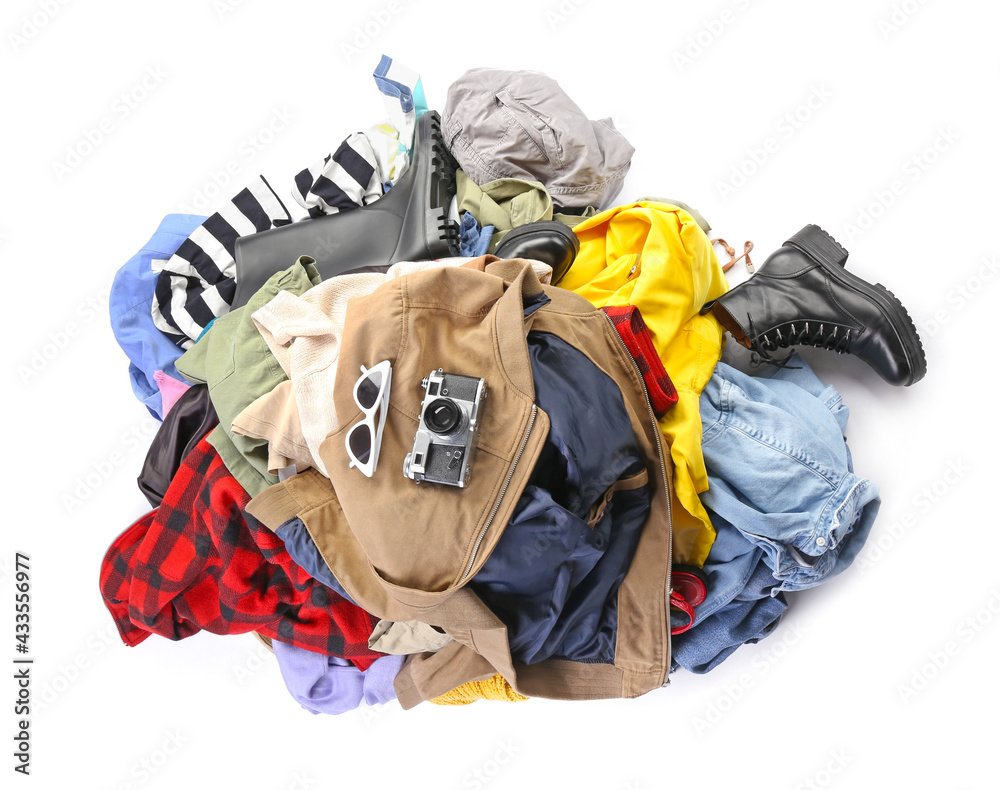 Sunglasses, photo camera and heap of different clothes on white background