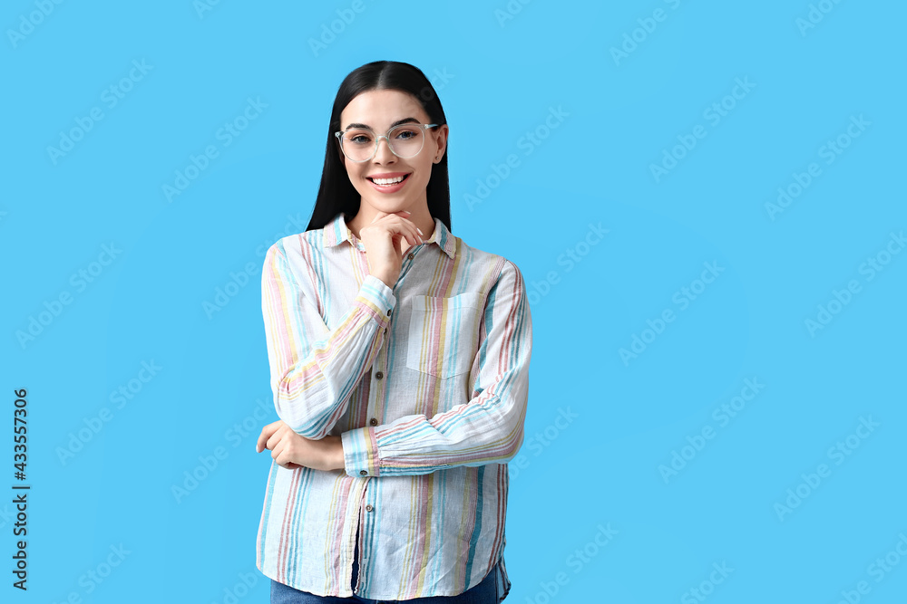 Beautiful young woman wearing eyeglasses on color background