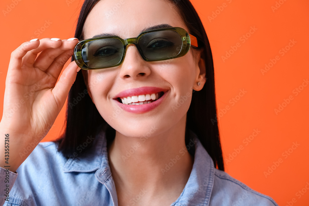 Beautiful young woman wearing stylish sunglasses on color background