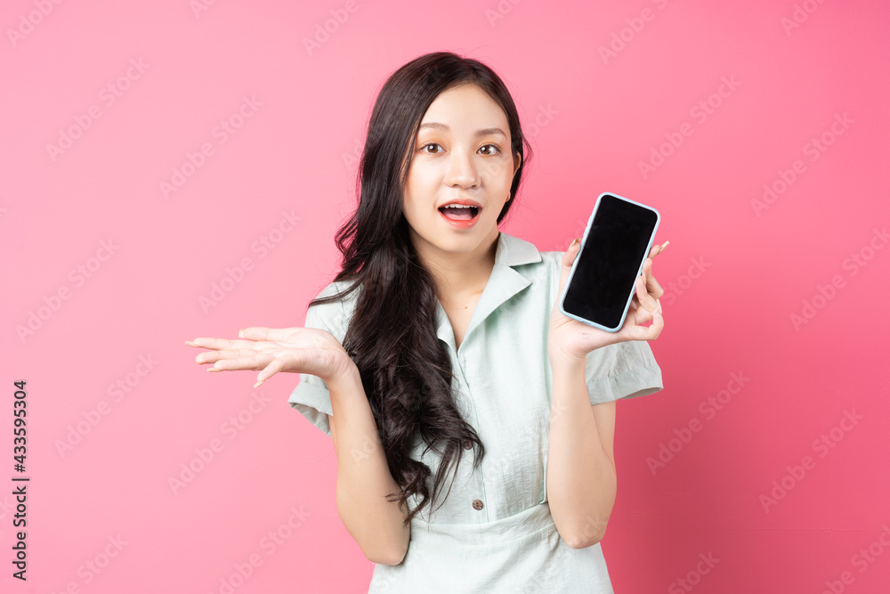 Young Asian woman holding phone in hand with surprised look