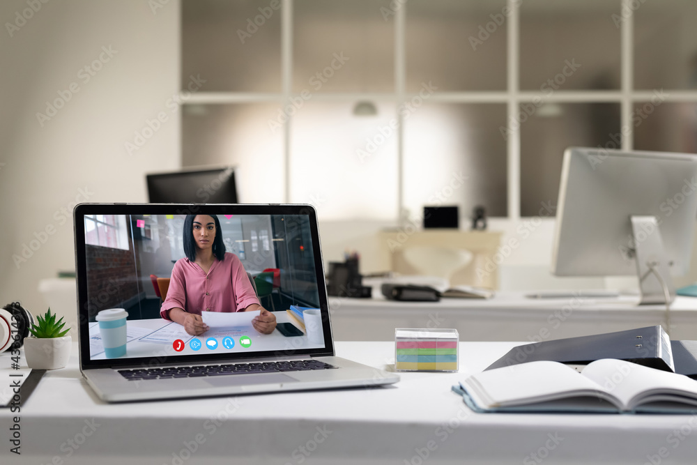 Laptop computer with a video call from businesswoman lying on desk