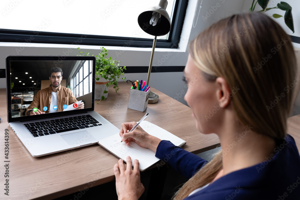 Caucasian businesswoman sitting at desk using laptop having video call with male colleague