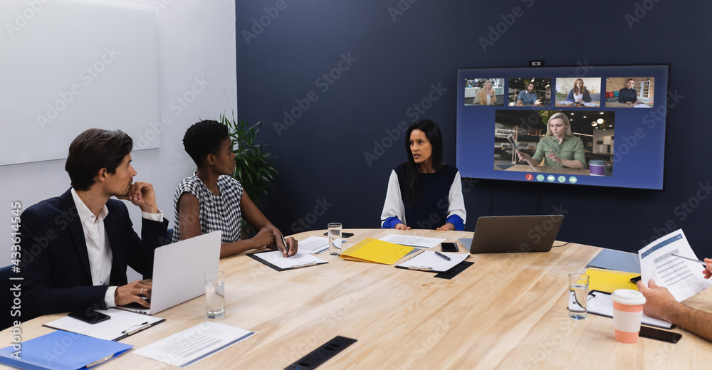 Diverse group of business colleagues having video call on screen in meeting room