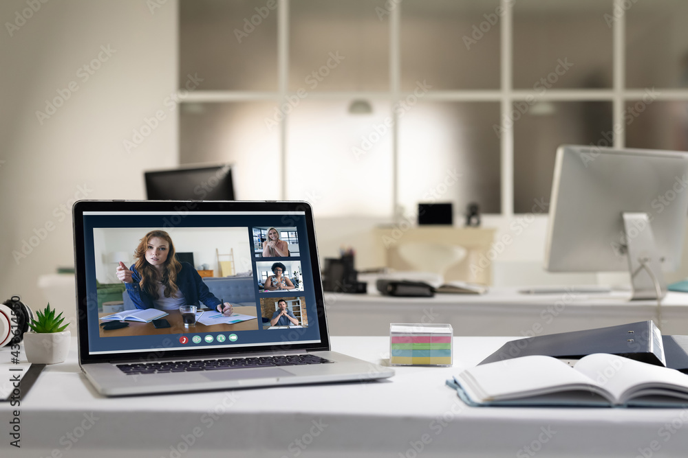 Laptop computer with a video call from businesspeople lying on desk