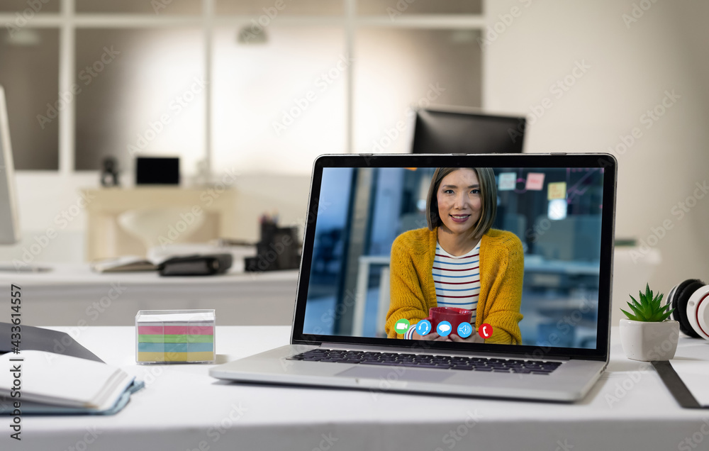 Laptop computer with a video call from businesswoman lying on desk