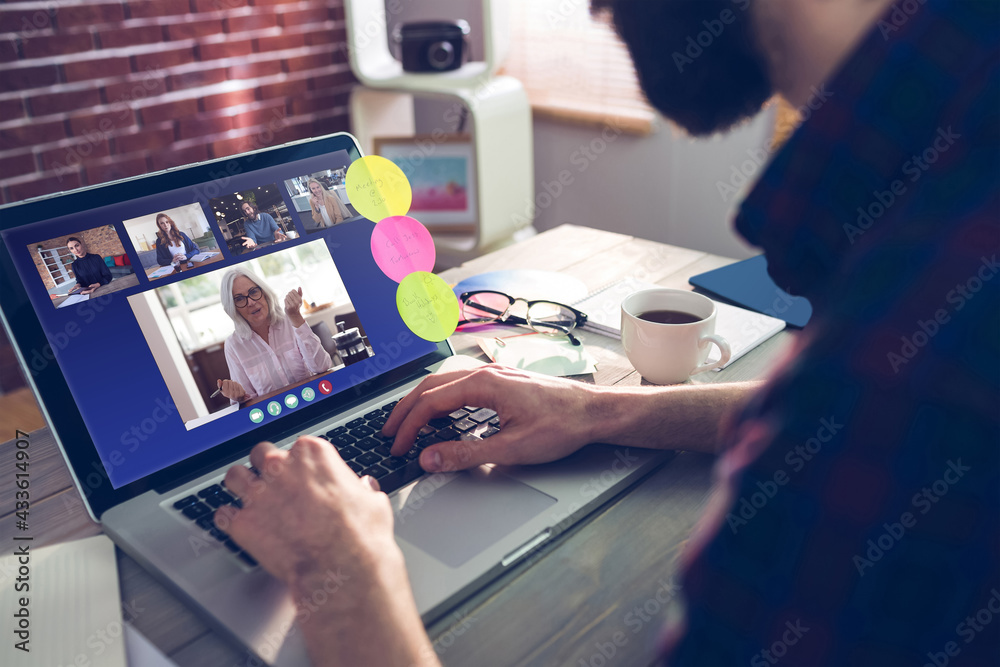 Caucasian businessman sitting at desk using laptop having video call with group of colleagues