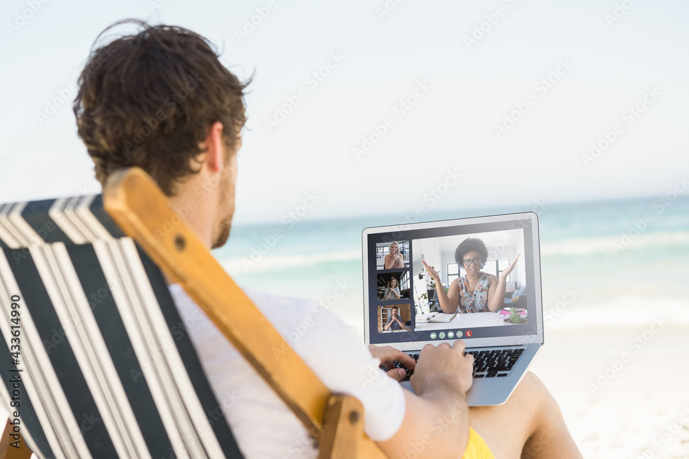 Caucasian man relaxing on beach having video call using laptop