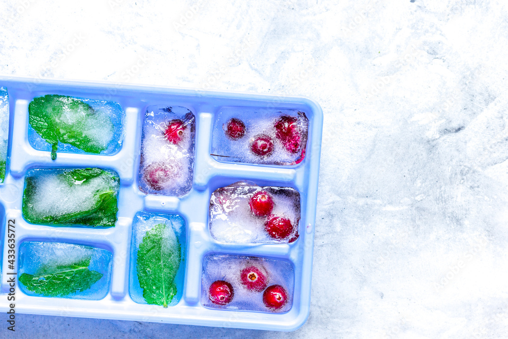 Ice cubes with berries and mint stone background top view mock up