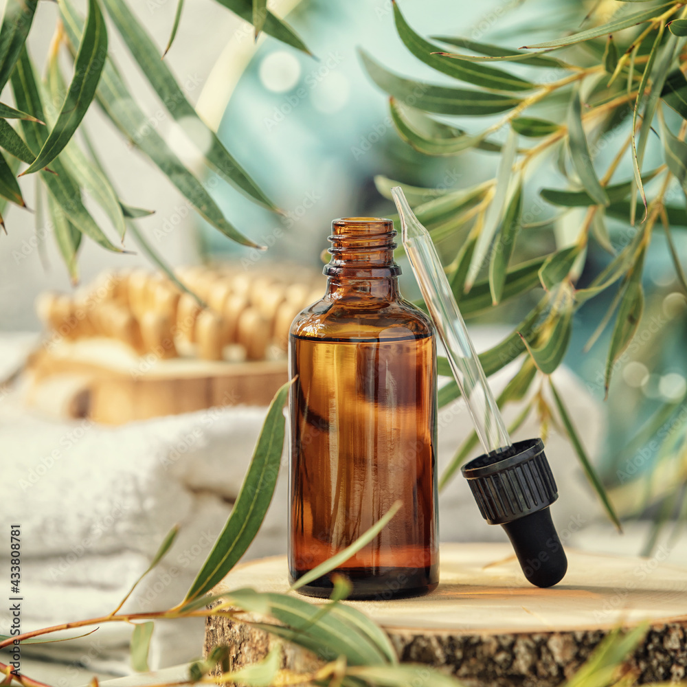 Amber glass bottle with wooden massage brush, eucalyptus leaves, mirror and towels