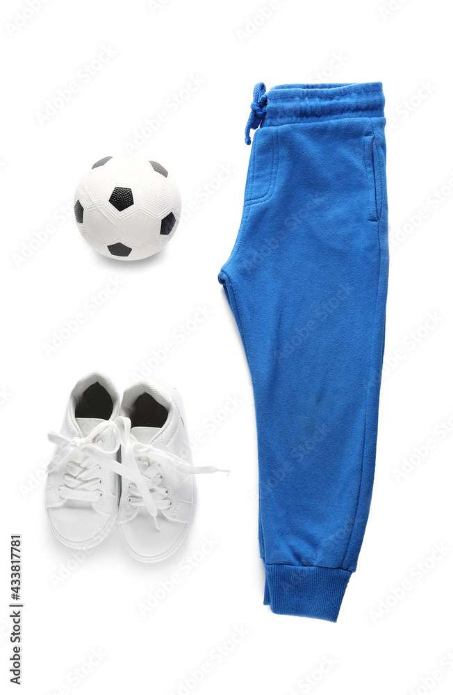 Childs pants, shoes and ball on white background