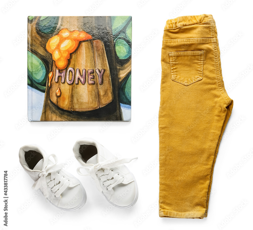 Childs pants, book and shoes on white background