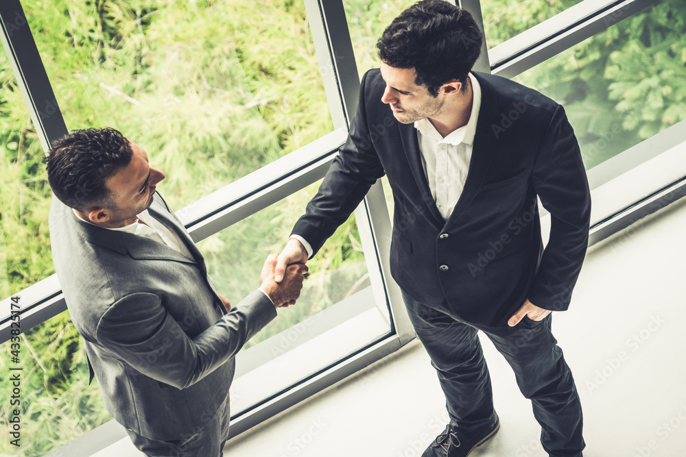 Businessman handshake with another businessman partner in modern workplace office. People corporate 